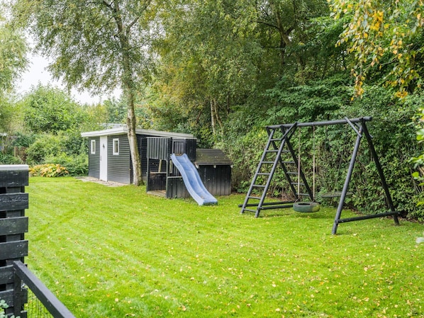 A backyard with a play area including a slide and a swing set.