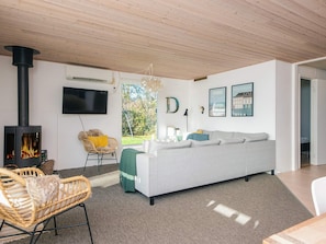 A modern living room with a fireplace, a sofa, a chair, and a television.