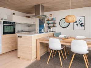 A modern kitchen with wooden cabinets, a built-in oven, and a central island with chairs. - 4 Star Holiday Home in Hemmet (Hemmet)