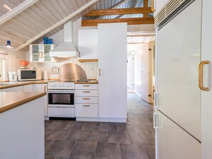 Une cuisine moderne avec des meubles blancs, une hotte en acier inoxydable et un four encastré.