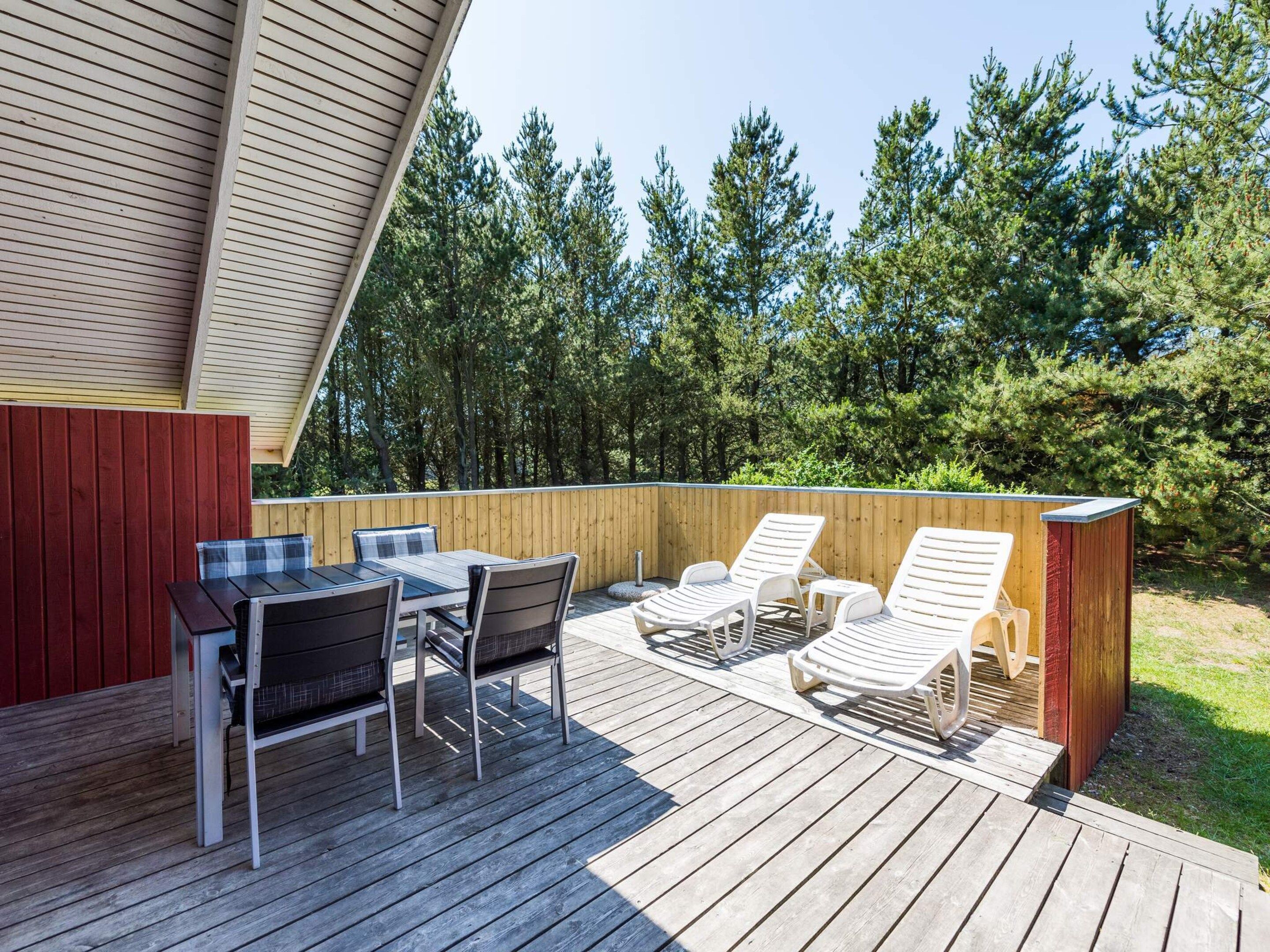 A wooden deck with a table and chairs, a small covered area, and a wooden structure.