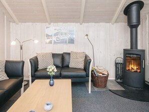Un salon chaleureux avec un canapé, une table basse, une cheminée et des œuvres d’art murales.