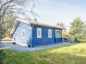 A log cabin with a sloped roof, a chimney, and a gravel driveway. - 5 Person Holiday Home in Norre Nebel (Norre Nebel)