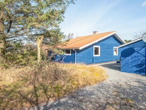 A blue wooden house with a gravel driveway and a small window. - 5 Person Holiday Home in Norre Nebel (Norre Nebel)