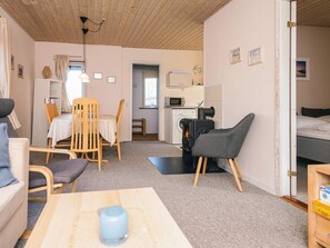 A compact living space with a dining area, a kitchenette, a bed, and a small table with a cup.