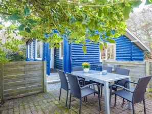 Une cabane en bois bleue dotée d’un patio, d’une table et de quatre chaises.
