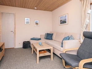 A cozy living room with a sofa, a chair, a coffee table, and a door. - 5 Person Holiday Home in Norre Nebel (Norre Nebel)