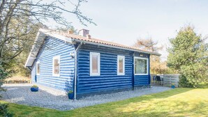 A log cabin with a sloped roof, two windows, and a gravel driveway. - 5 Person Holiday Home in Norre Nebel (Norre Nebel)
