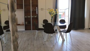 A dining area with a glass table, four chairs, a vase with flowers, and a stone sculpture. - Holiday Apartment near Lake, Shared Swimming Pool (Lazise)