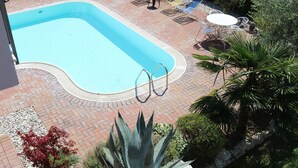 A swimming pool with a tiled deck, surrounded by lounge chairs and a small table. - Holiday Apartment near Lake, Shared Swimming Pool (Lazise)