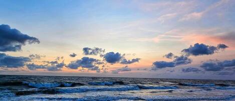 Ein Strand mit Wellen und einem Sonnenuntergangshimmel.