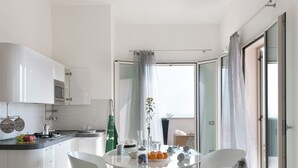 Una cocina moderna con armarios blancos, una mesa de comedor con sillas y vistas al exterior a través de un ventanal.