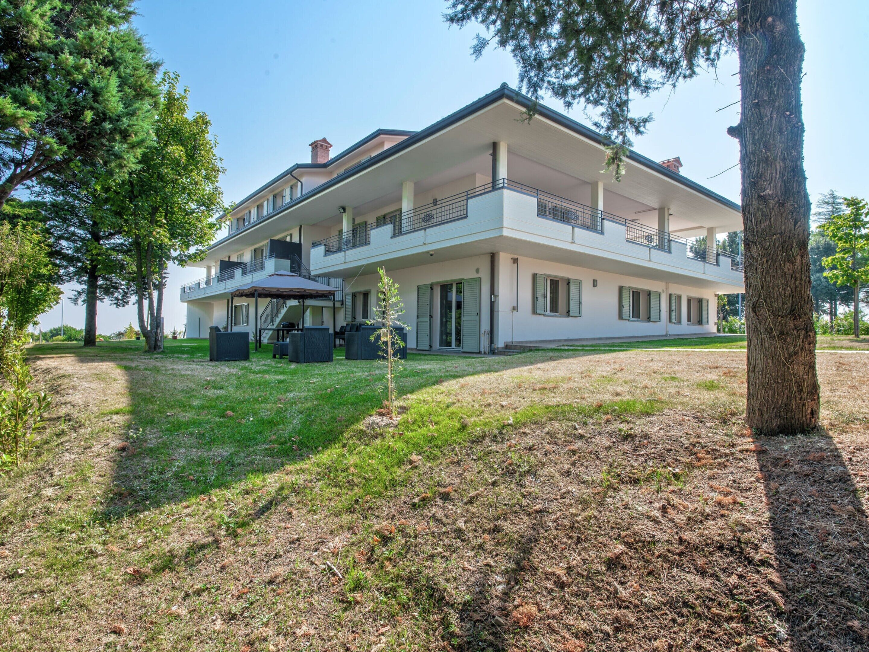 A two-story building with a balcony, outdoor seating, and a small garden area.