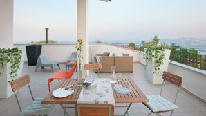 Una terraza con mesa lista para comer, sillas, un sofá y vistas al paisaje.