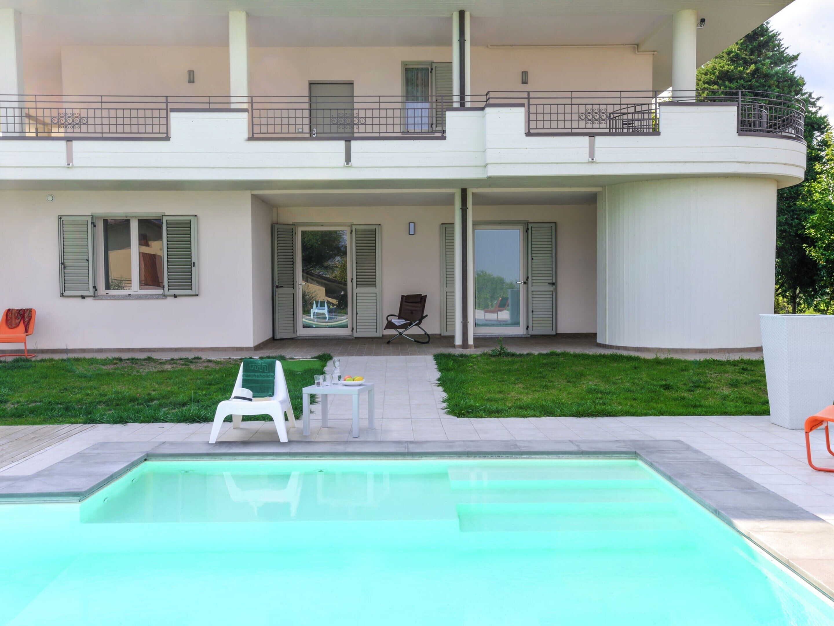 Un bâtiment à deux étages doté d’une piscine, d’un espace extérieur aménagé et d’un patio couvert.