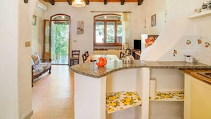 Una cocina con una isla central, vigas de madera en el techo y vista a un comedor.
