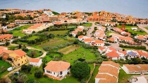 Vista aérea de una zona residencial costera con casas, áreas verdes y vistas al mar.