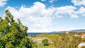 Vista desde un balcón sobre un jardín, con cielo despejado y montañas a lo lejos.