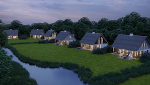 En række moderne huse med store vinduer og en grøn græsplæne foran.