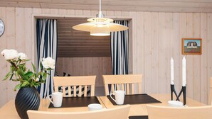 A wooden-paneled room with a dining table, chairs, a vase with flowers, a clock, and a framed picture on the wall. - 6 Person Holiday Home in Tarm (Tarm)