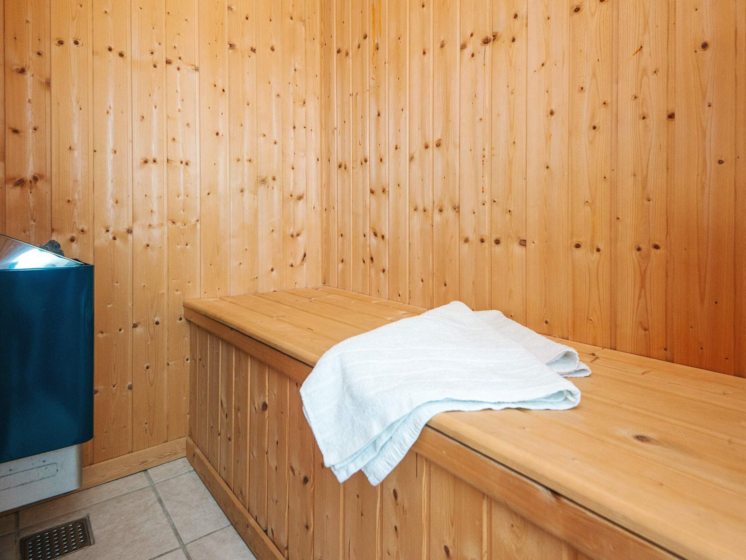 A sauna room with wooden walls, a bench, and a towel.