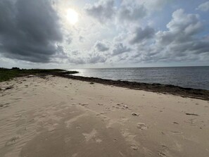 A beach with footprints in the sand and a cloudy sky.