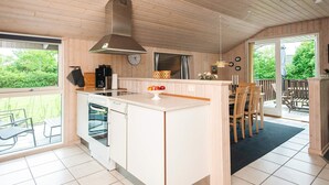 A modern kitchen with a central island, a built-in oven, and a large window overlooking a garden. - 6 Person Holiday Home in Tarm (Tarm)