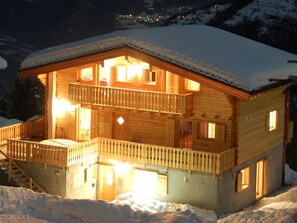 Eine zweistöckige Holzchalet mit Balkon, umgeben von Schnee.