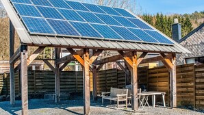 A covered outdoor area with a solar panel array, wooden benches, and a gravel ground. - Timeless Cottage in Vresse-sur-semois With Terrace (Vresse-sur-Semois)