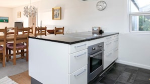 A modern kitchen with a central island, white cabinetry, stainless steel appliances, and a glass ceiling vent.