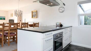 A modern kitchen with a central island, stainless steel appliances, and a glass pendant light.