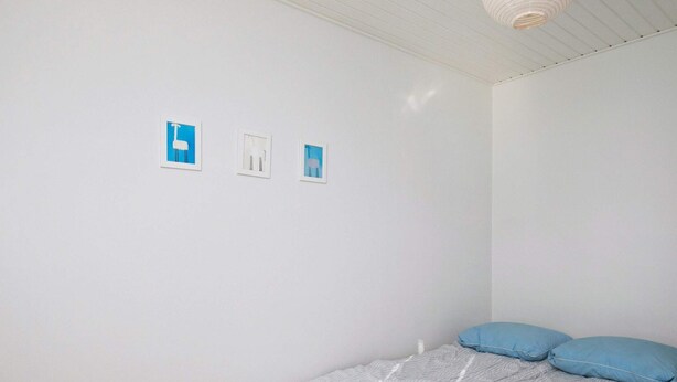 A bedroom with a bed, pillows, and three framed pictures on the wall.