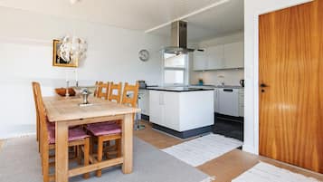 Eine moderne Küche mit weißen Schränken, einem Holztisch und einer Uhr an der Wand.