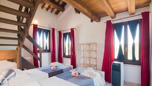 A room with two beds, a wooden staircase, and a radiator. - Scenic Apartment in Ascoli Piceno with Hot Tub (Ripatransone)