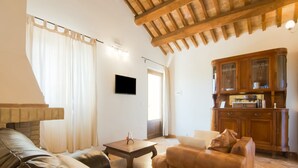 A living room with a fireplace, leather sofas, a wooden cabinet, and a television. - Scenic Apartment in Ascoli Piceno with Hot Tub (Ripatransone)