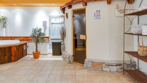 A bathroom with a wooden bathtub, a potted plant, a stone wall, and a towel rack. - Apartment in Grossarl Near Ski Slopes (Grossarl)