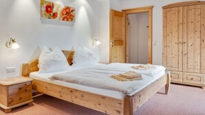 A wooden bed with white bedding, a nightstand, a wooden wardrobe, and a wall-mounted artwork. - Apartment in Grossarl Near Ski Slopes (Grossarl)