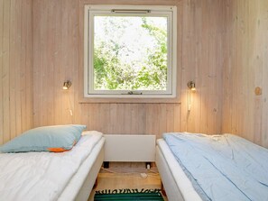 A room with two beds, a window with a view of greenery, and wall-mounted lights. - 8 Person Holiday Home in Tranekaer (Tranekaer)
