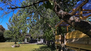 A wooden deck with a pergola, a grassy yard, and a small pavilion.
