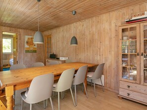 A wooden-paneled room with a long dining table, chairs, and a cabinet with glass doors. - 8 Person Holiday Home in Tranekaer (Tranekaer)
