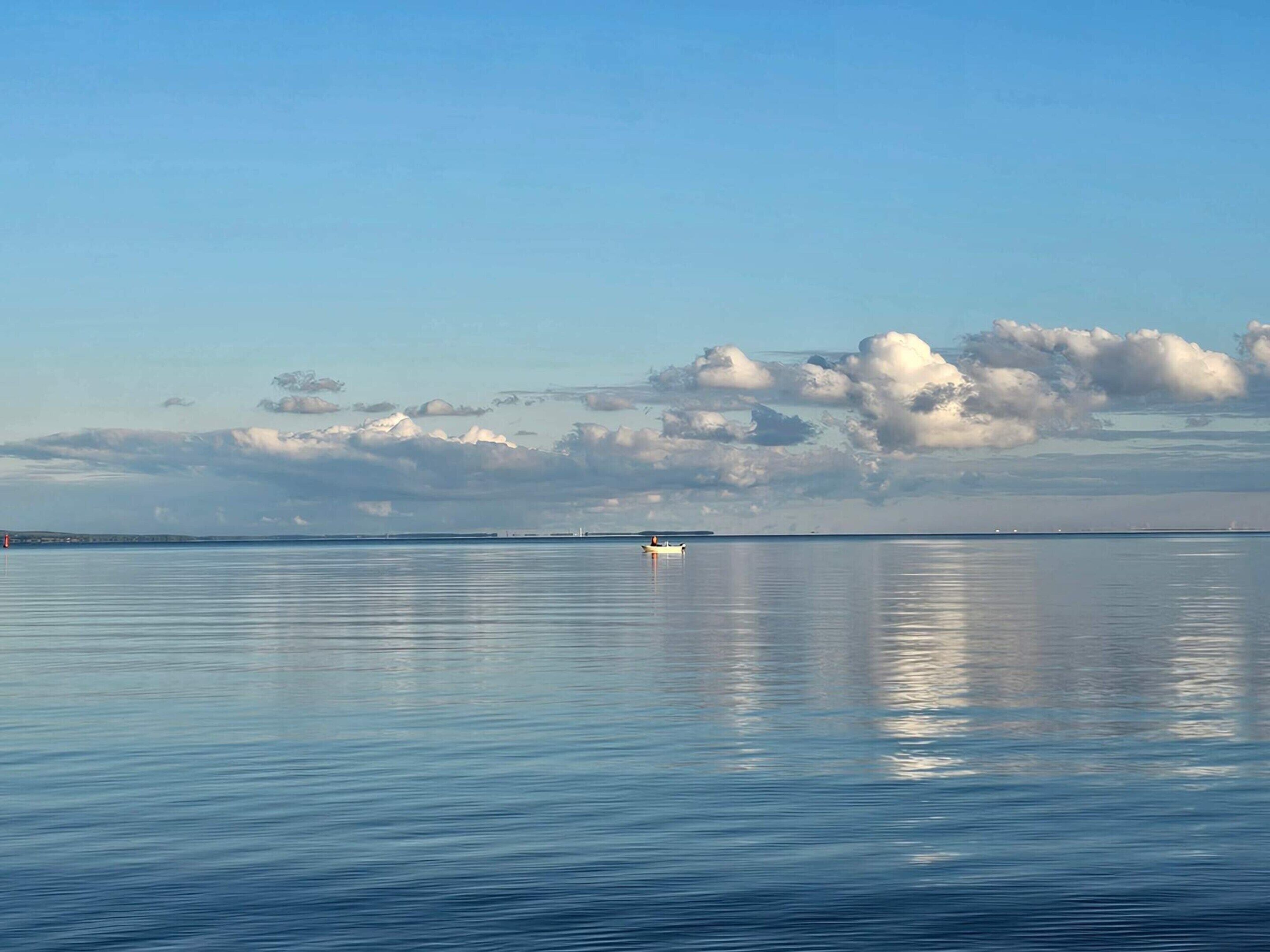 Água calma com um barco e terra ao longe.