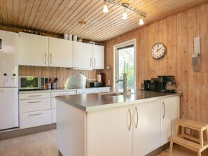 A modern kitchen with white cabinets, a stainless steel refrigerator, a microwave, and a coffee maker. - 8 Person Holiday Home in Tranekaer (Tranekaer)
