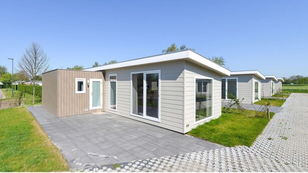 Una hilera de modernas casas móviles de un solo piso, con ventanas grandes y techo plano.