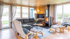 Een gezellige woonkamer met een bank, stoelen, een televisie en een houtkachel.