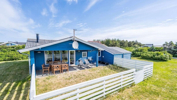 Een blauw huis met terras, een witte schutting en een schotelantenne.