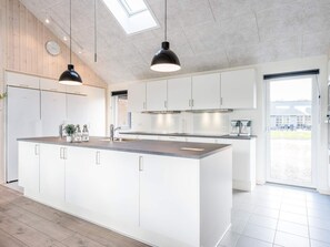 Una cocina moderna con una isla central, muebles blancos y un tragaluz.