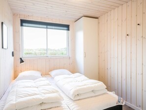 A room with a bed, a window, and wooden walls.