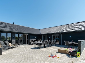 Un patio techado con mobiliario exterior y una zona de juegos.
