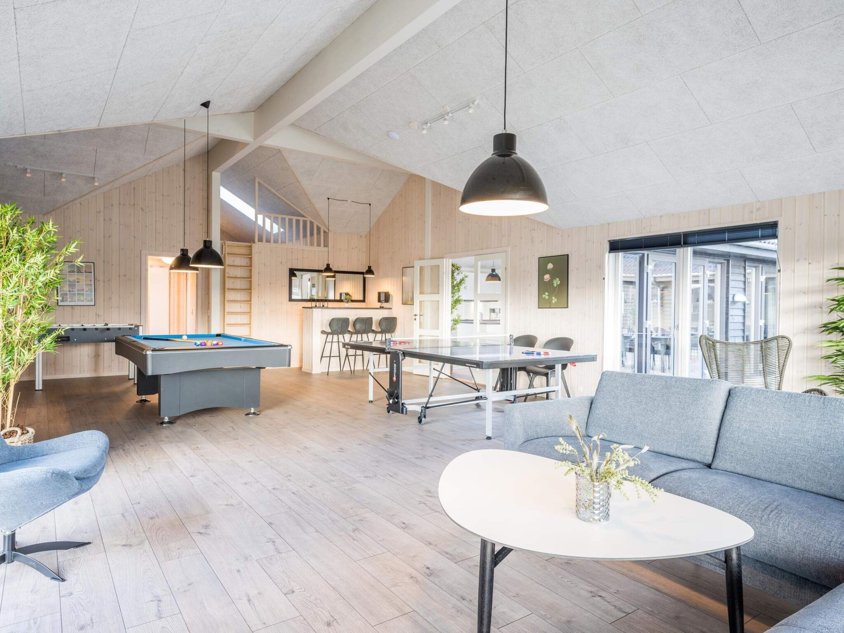 A spacious living area with a pool table, a sofa, and a dining table with chairs.