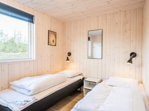 Una habitación con dos camas, una mesita, una ventana y un espejo.